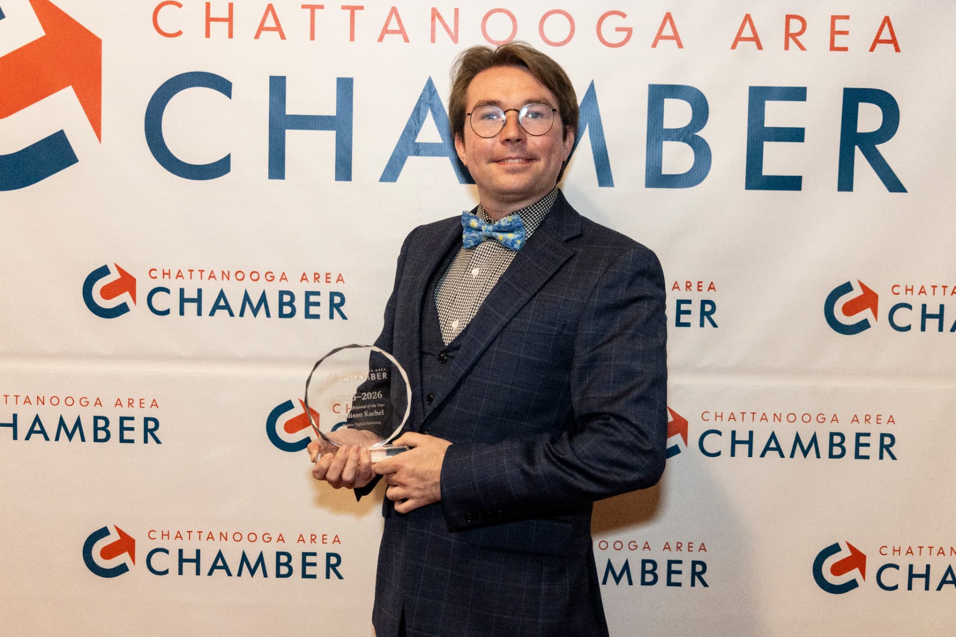 Madison Kachel holding his Young Professional of the Year award in front of the Chattanooga Area Chamber backdrop.